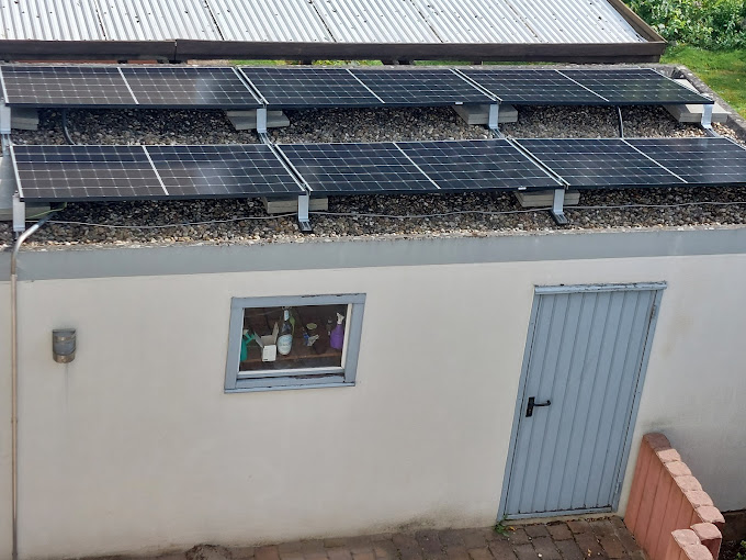 Solarpanels sind auf dem Dach eines Gebäudes installiert, das eine Fensterscheibe und eine Metalltür zeigt.