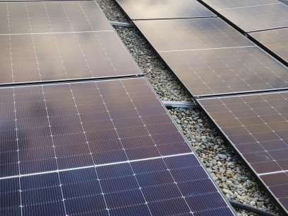 Reihen von Solarpanels auf einem Kiesbett unter einem bewölkten Himmel.