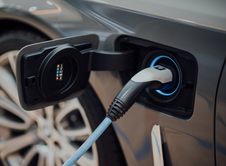 Ein Elektroauto wird an einer Ladebuchse mit einem blauen Ladekabel geladen.